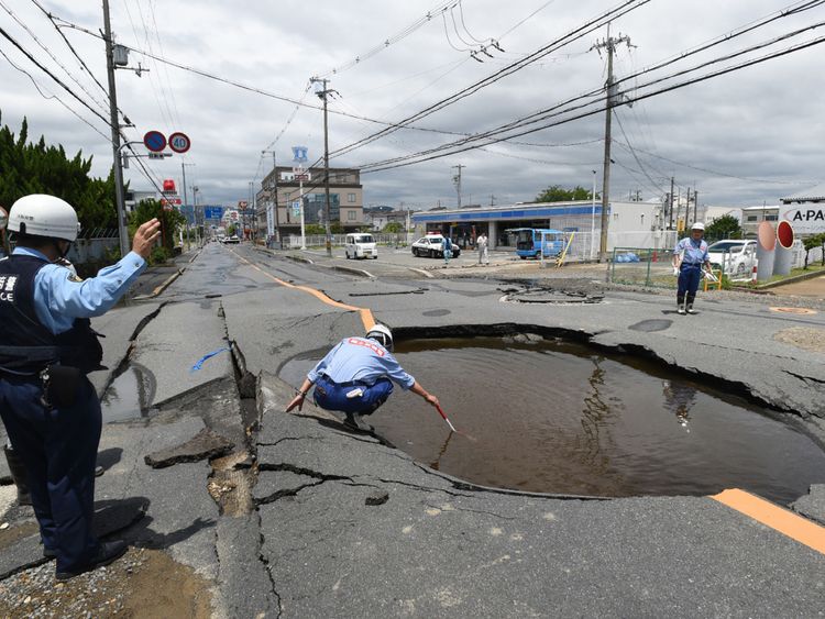Police check a collapsed road following an earthquake in Takatsuki, north of Osaka, Japan