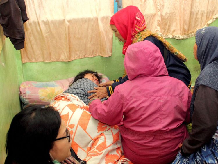 A survivor is surrounded by family members after she was rescued from the ferry