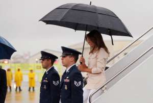 a group of people standing in the rain holding an umbrella: U.S. first lady Melania Trump arrives at airport near the U.S.-Mexico border in McAllen, Texas