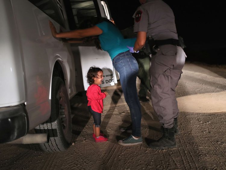 A toddler cries as her mother is searched at the border