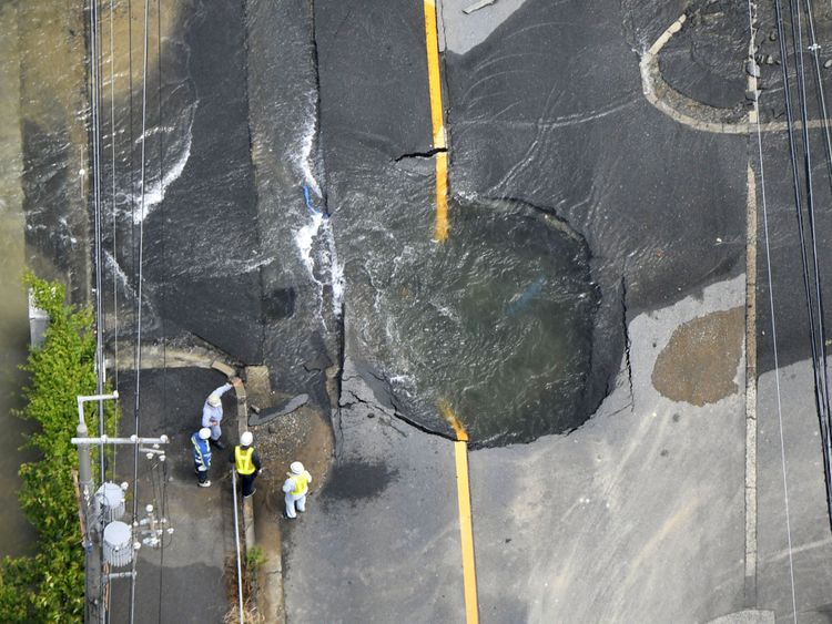 Water flows out from cracks in a road damaged by the earthquake